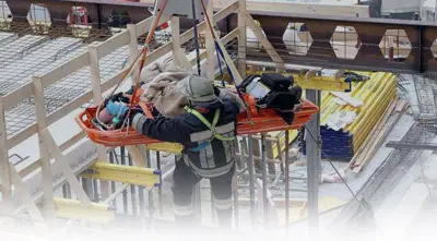 Rescue worker lifts stretcher at construction site.