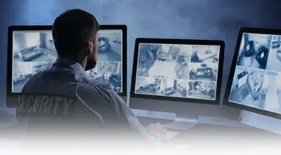 Security guard monitoring surveillance screens.