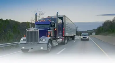 Semi-truck and car on highway at sunset
