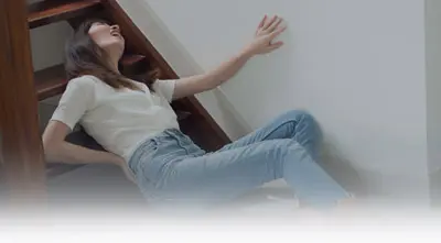 Woman sitting on stairs holding back in pain.