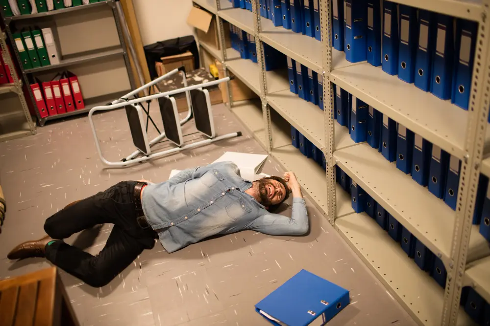 Man fallen beside overturned chair in office.