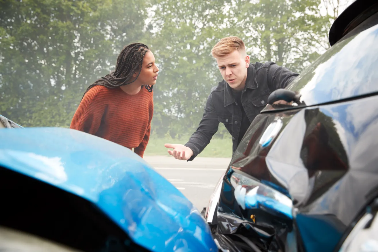 Two people discussing minor car accident damage.